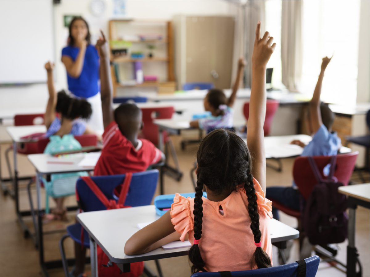 students raising hands in engaged classroom
